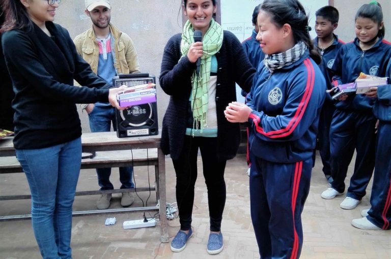 A woman carries a small boy and a bright yellow water container